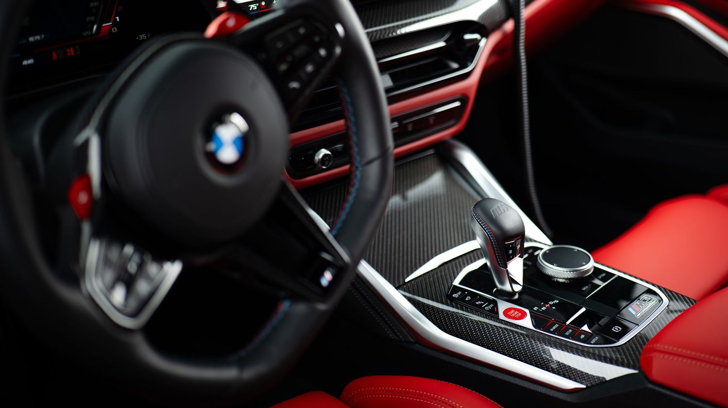 Interior view of a BMW showing red leather seats and black dashboard with modern controls.