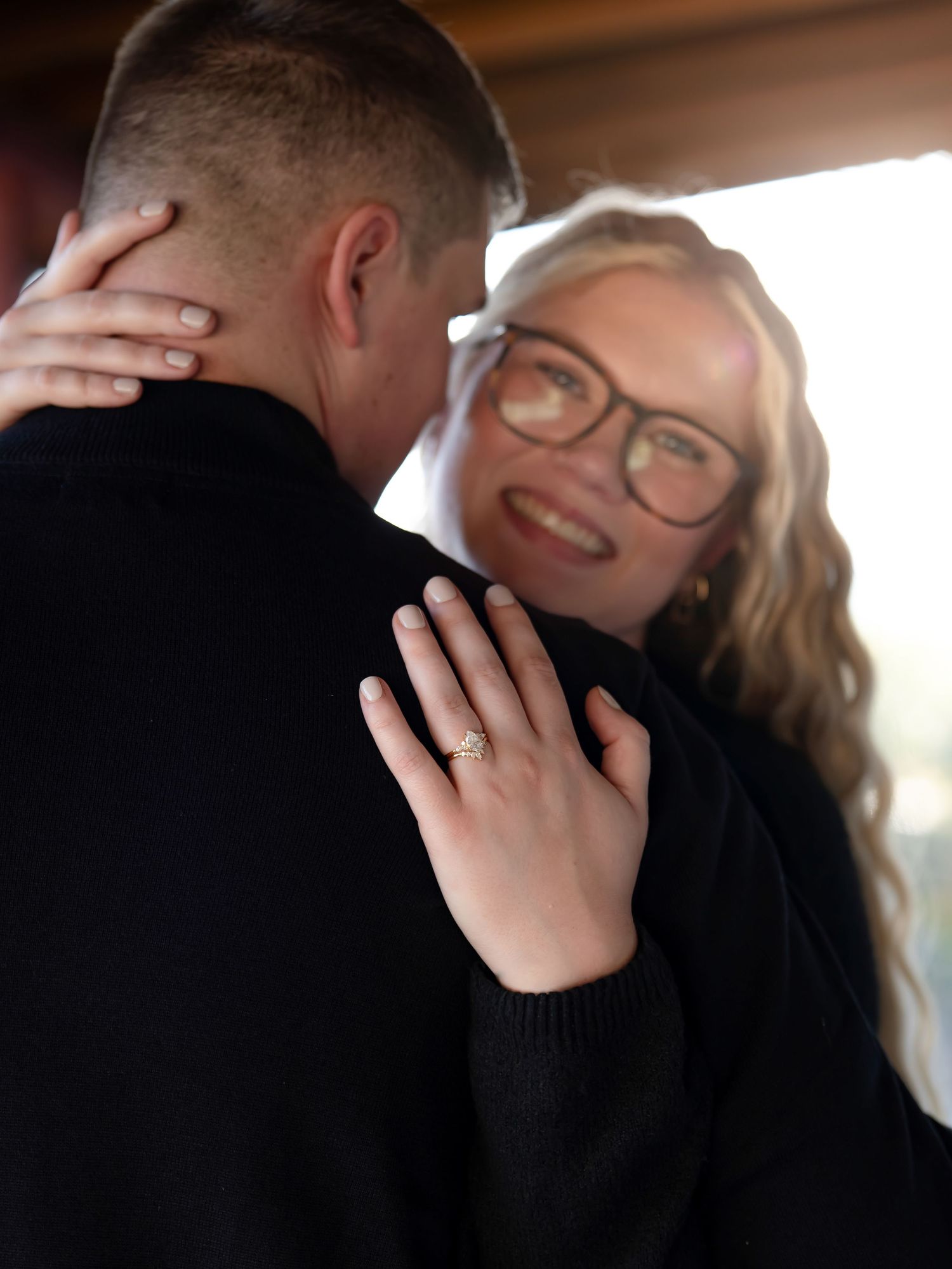 A close-up shot showing hands embracing and a sparkling engagement ring.