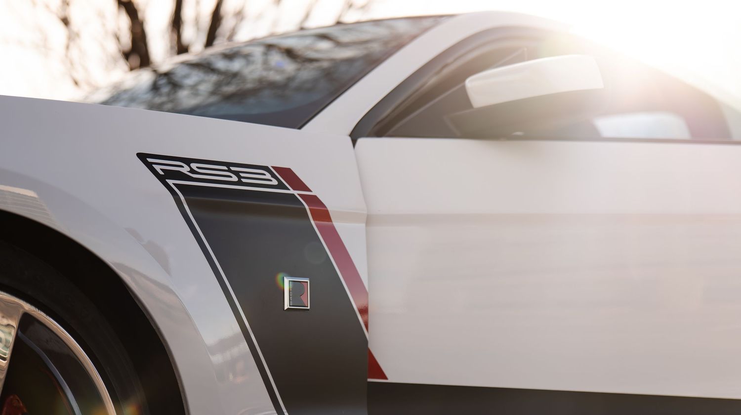 Close-up panoramic detail of white sports car bodywork in sunlight.