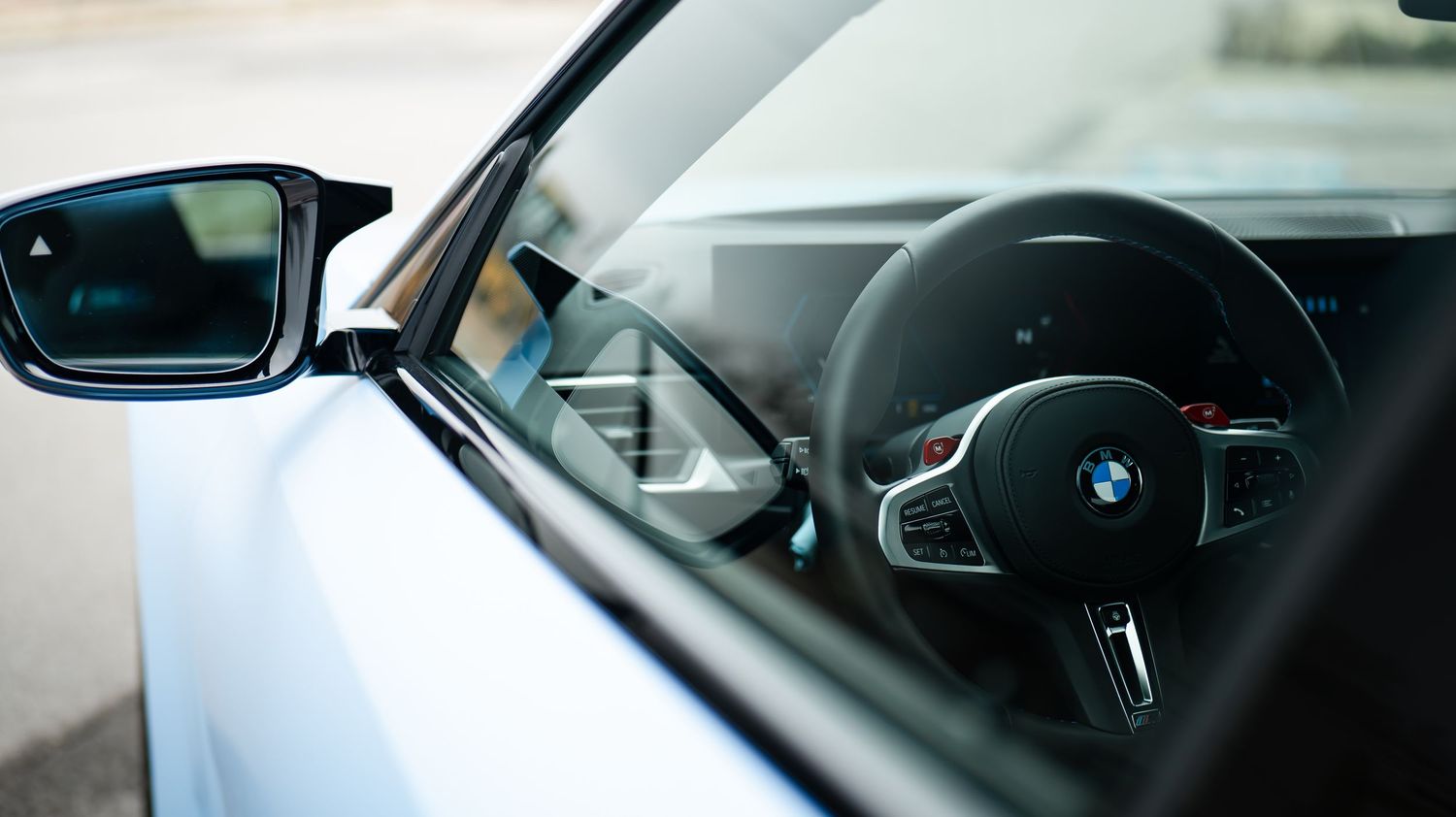 Modern BMW interior showing steering wheel and dashboard controls.