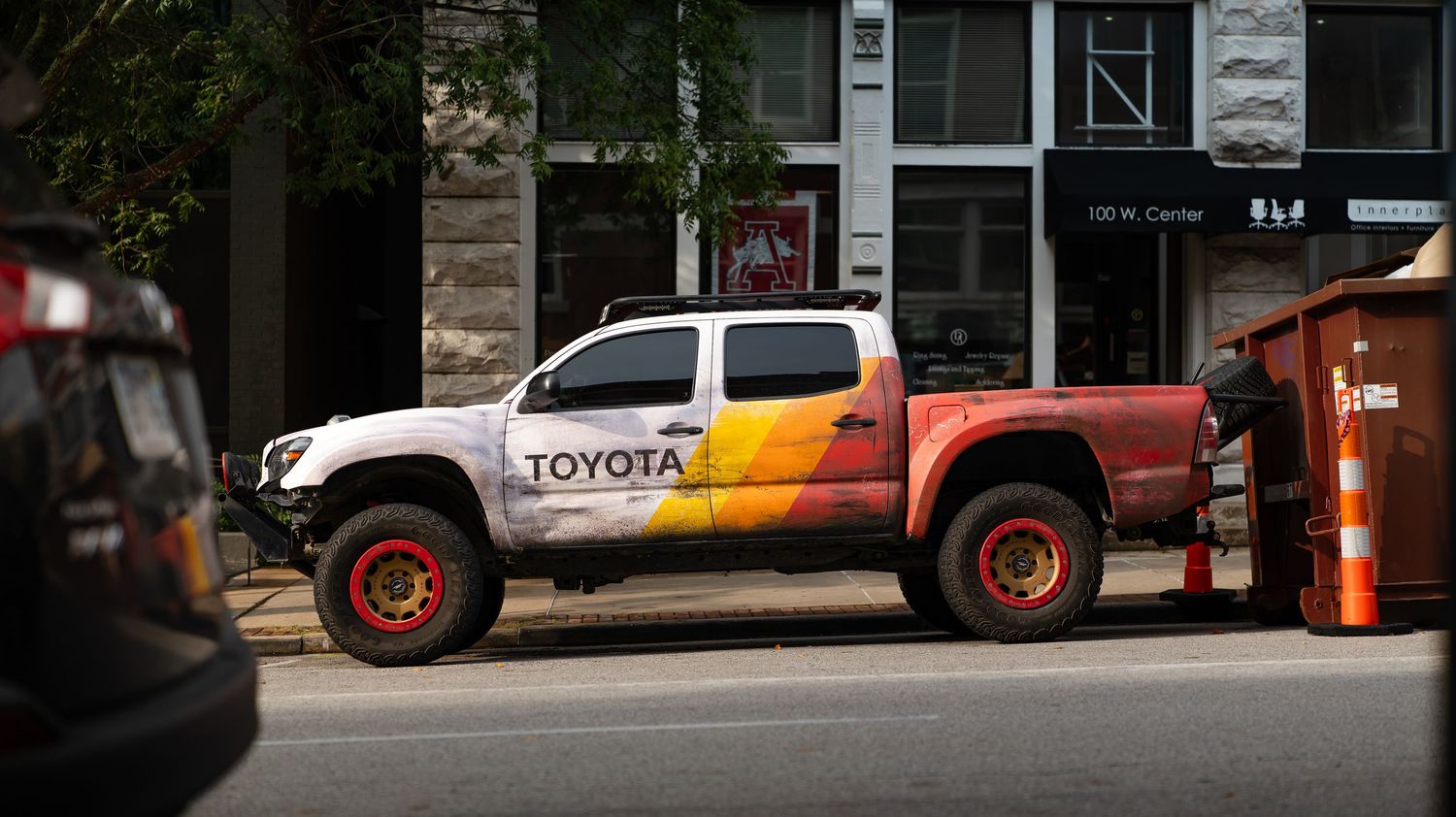 Custom Toyota pickup truck with orange flames displayed at outdoor car show.