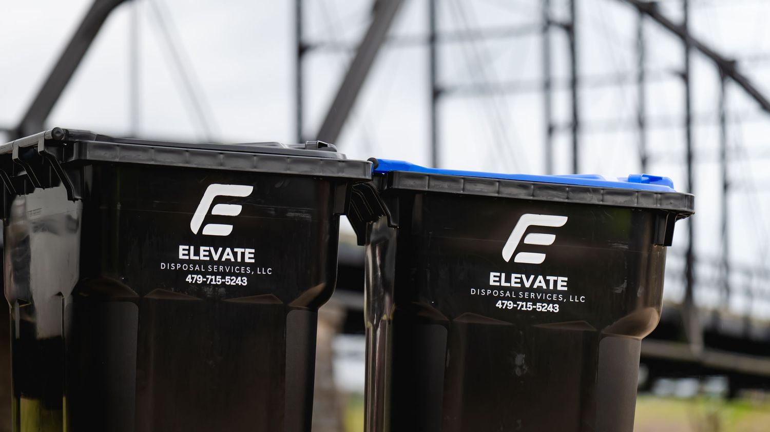 Row of black industrial waste containers with Elevate company branding.