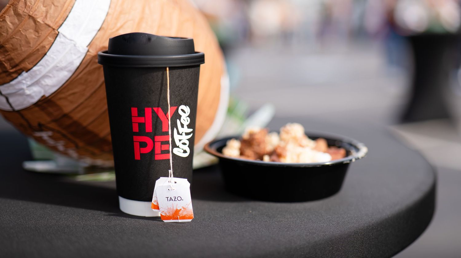 Row of disposable coffee cups and food items displayed on a counter surface.
