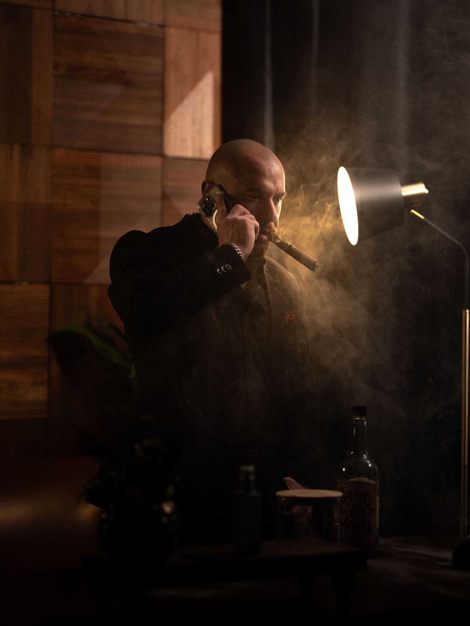 Silhouetted figure smoking in dark atmospheric room with beams of light creating moody ambiance.