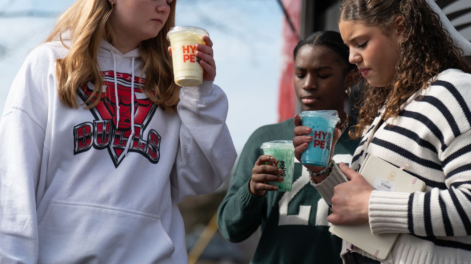 People in casual wear holding beverages outside a building.