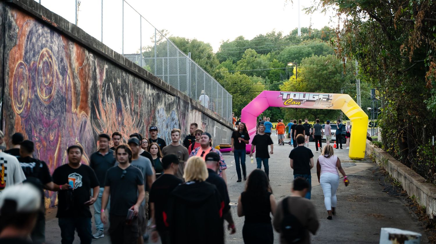 Long walkway with graffiti art and people walking along a barrier wall.