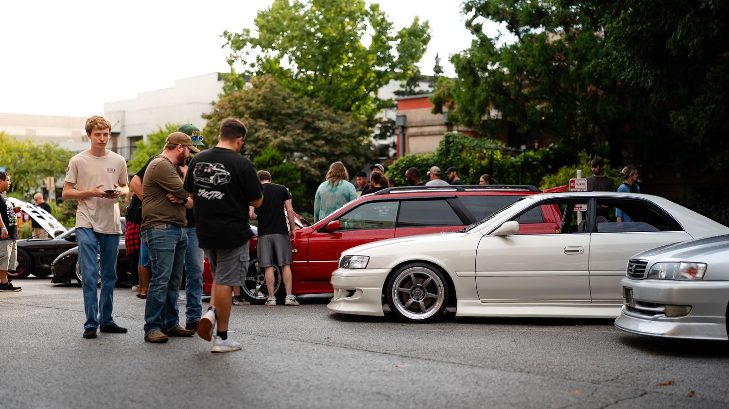 Wide panoramic view of cars lined up at an outdoor auto show.