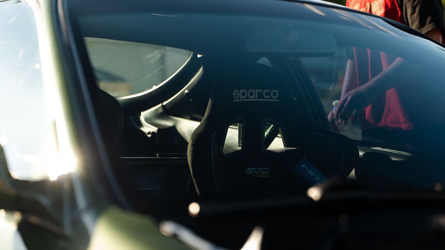 Racing seat visible through car window with Sparco branding.