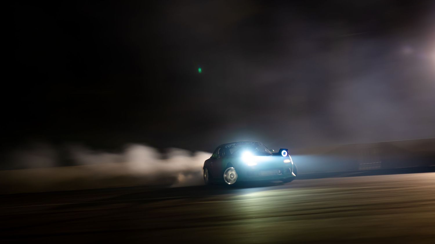 Motion-blurred nighttime shot of car headlights on dark road.