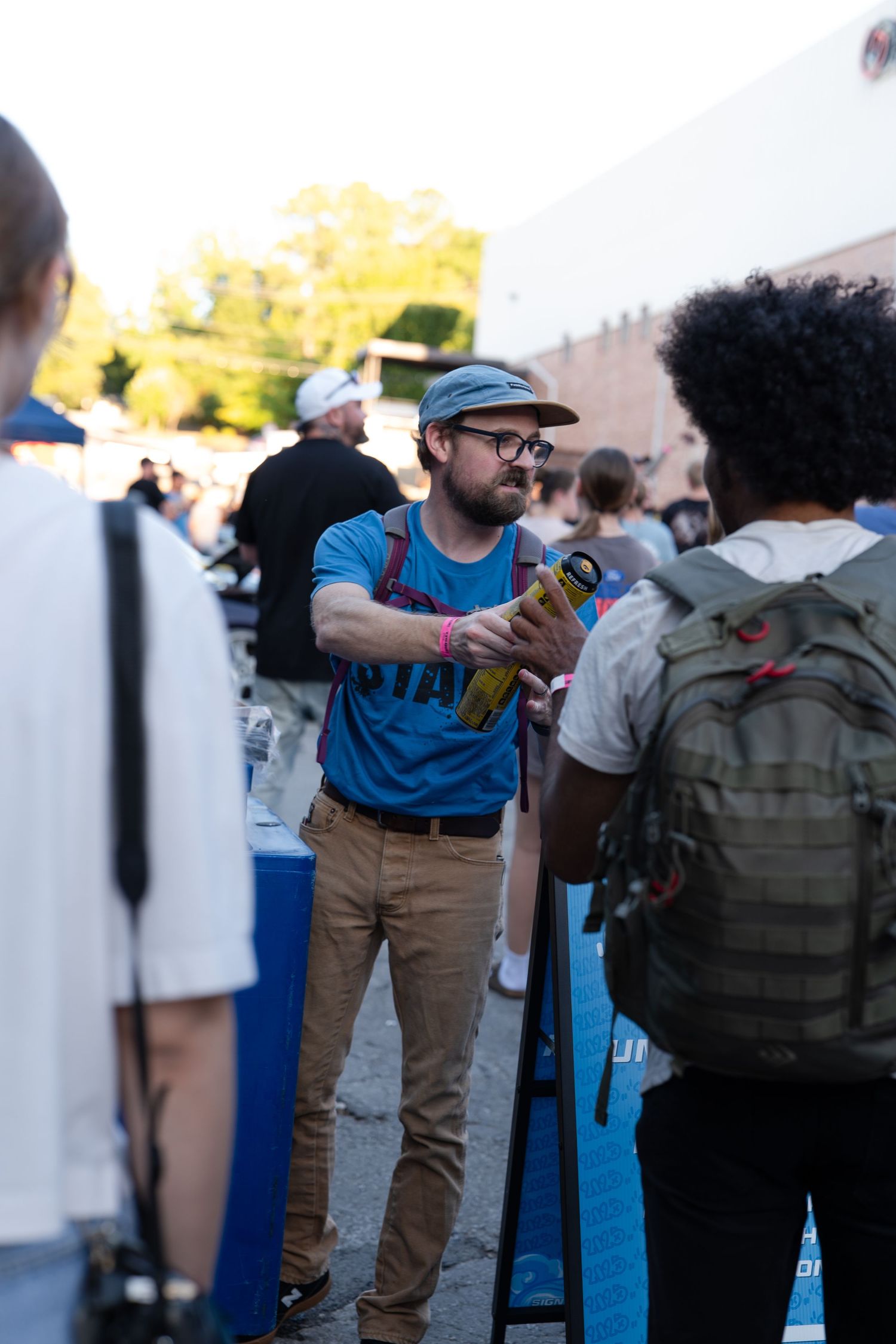 Event attendees gathered around blue coolers at an outdoor gathering.