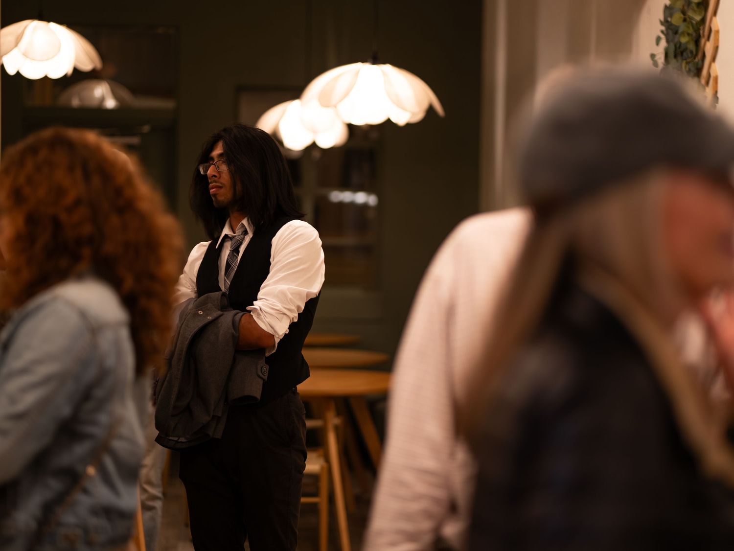 A group of people stand in a dimly lit room with warm lighting and elegant decor.