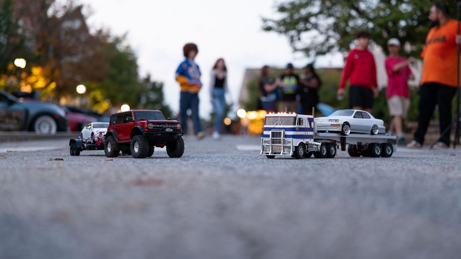 Remote controlled toy cars lined up on a street during a public event.
