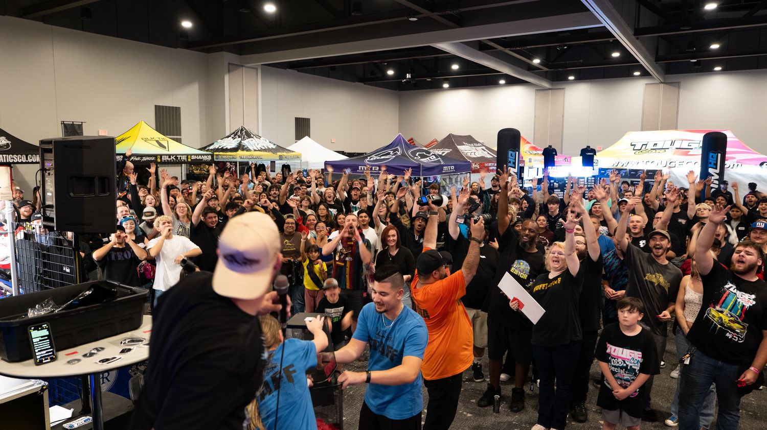 Panoramic view of a packed gaming convention hall with vendor booths and overhead lighting.