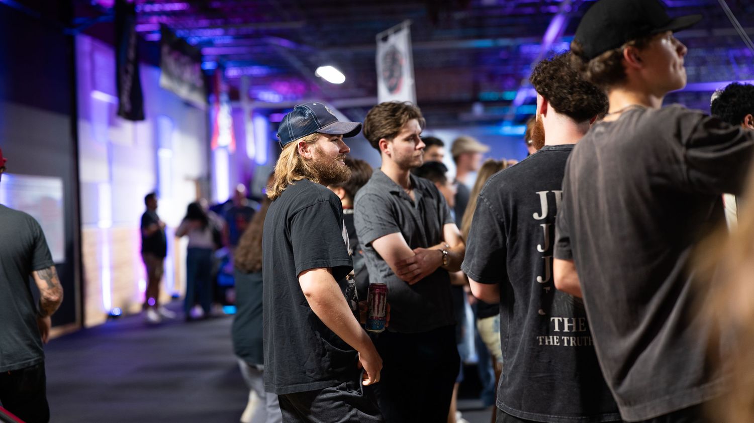 Indoor car show event with purple ambient lighting and attendees.