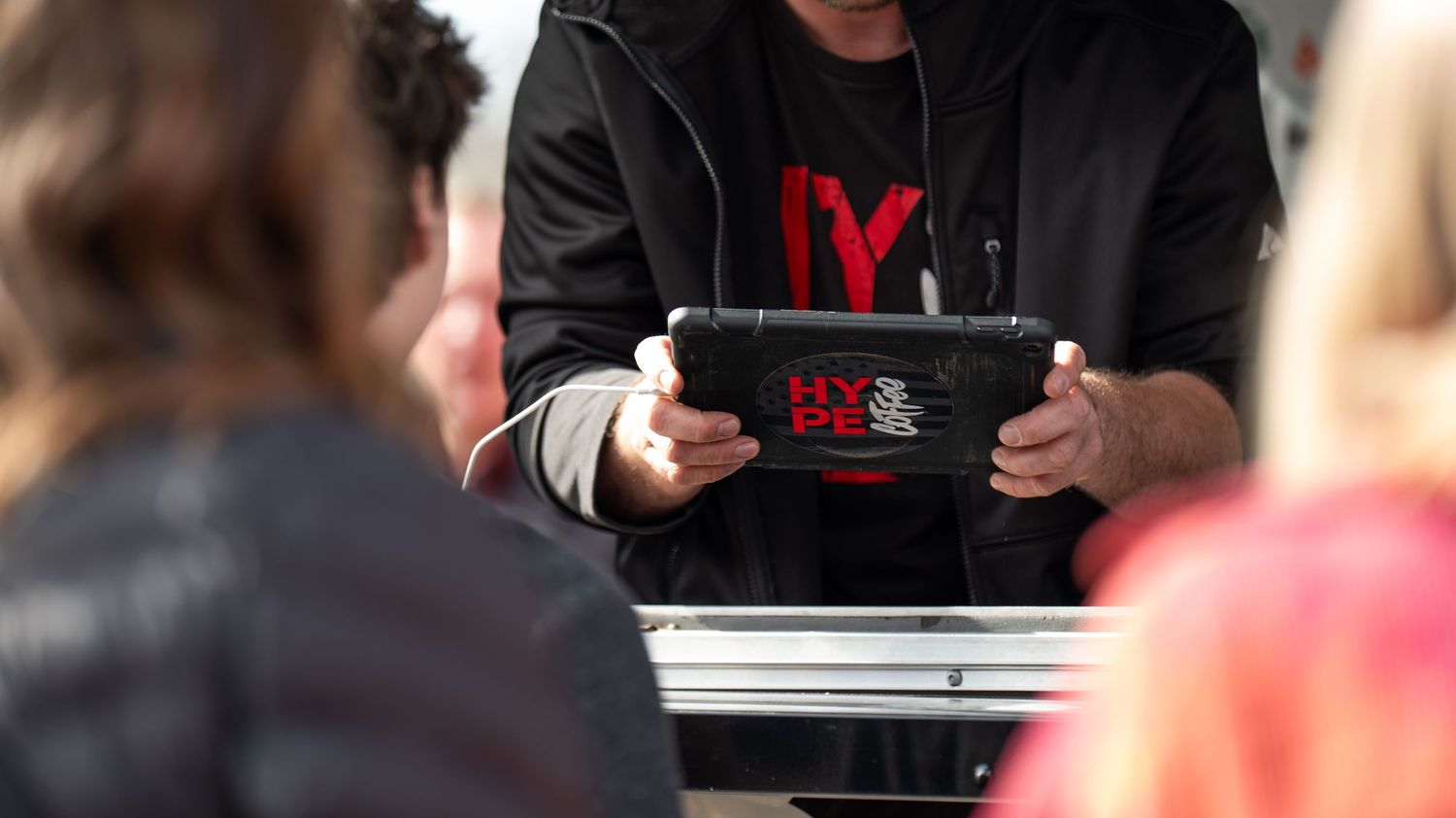 Customers receiving beverages and snacks at an outdoor service counter.