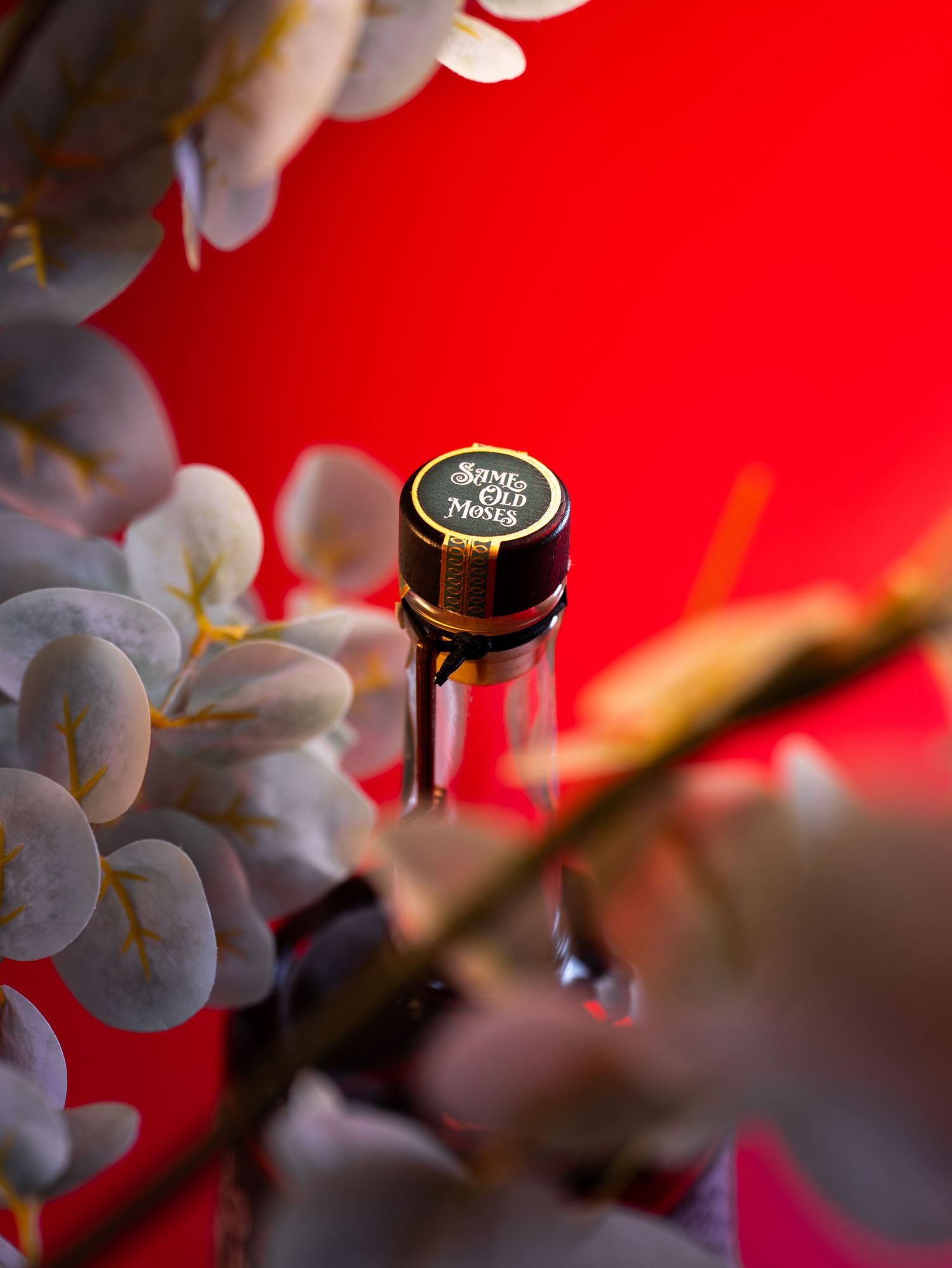Close-up shot of a wine bottle cap with blurred white grapes against a vibrant red background.