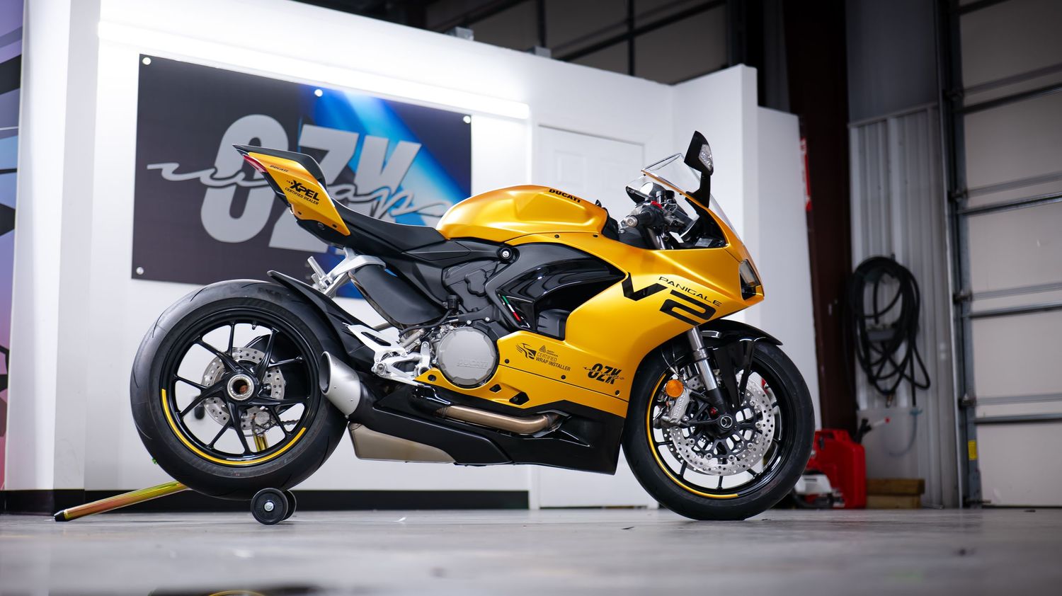 Yellow Ducati sportbike displayed in a clean white workshop environment.