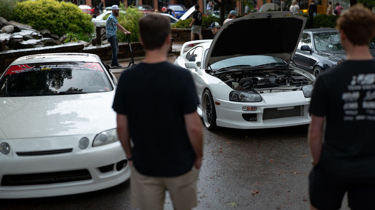 Modified cars on display at an evening automotive gathering.