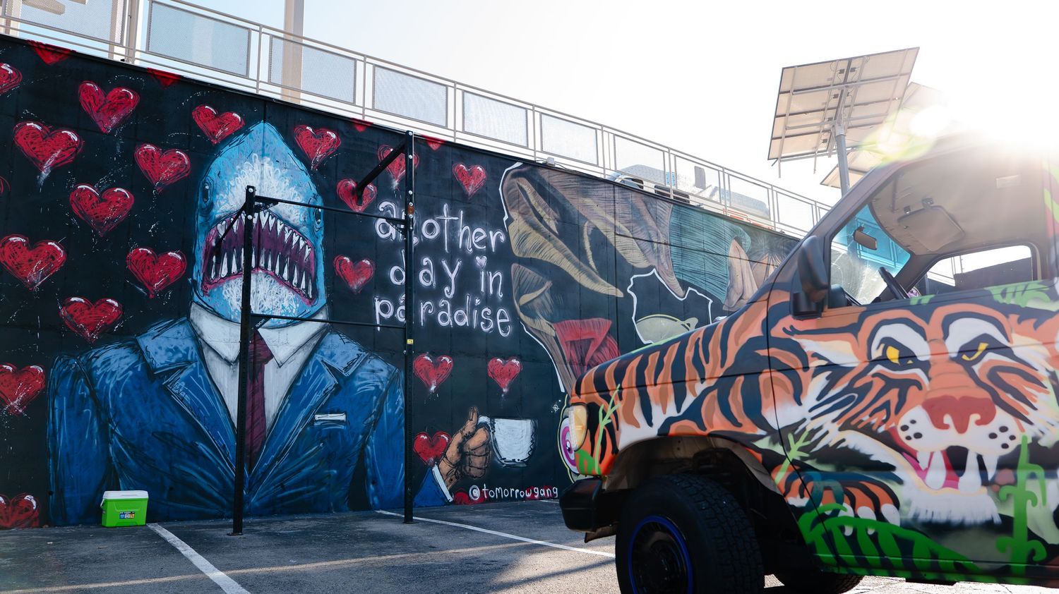 Colorful street art mural featuring shark character and hearts on outdoor wall.