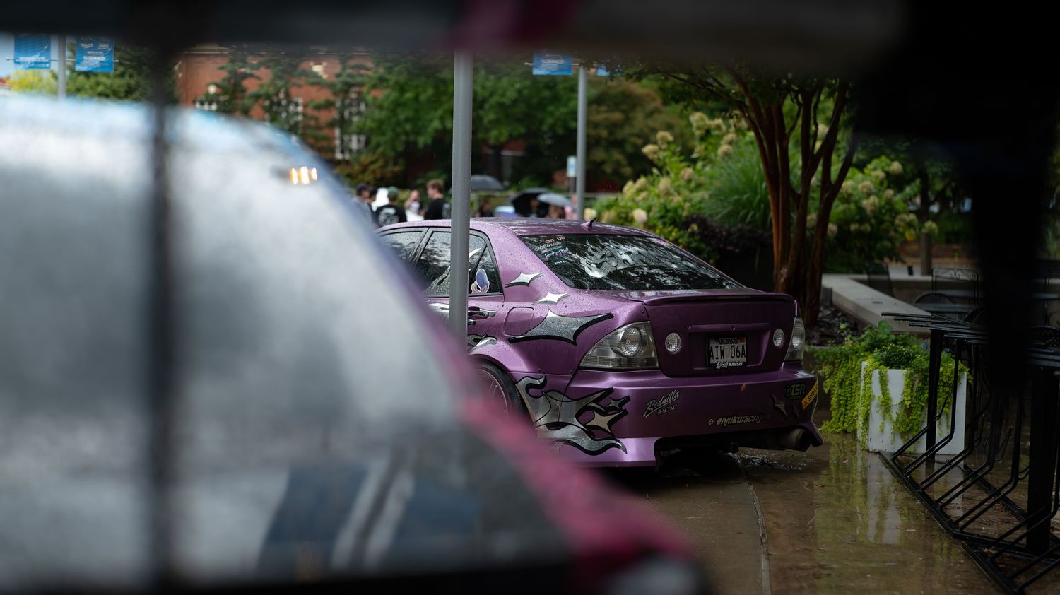 Panoramic view of cars parked at a car meet during golden hour with trees in background.