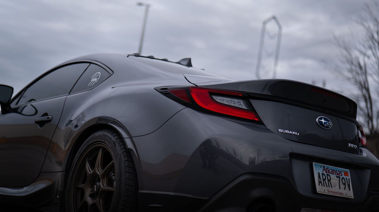 Panoramic view of a lowered gray sports car against an overcast sky.