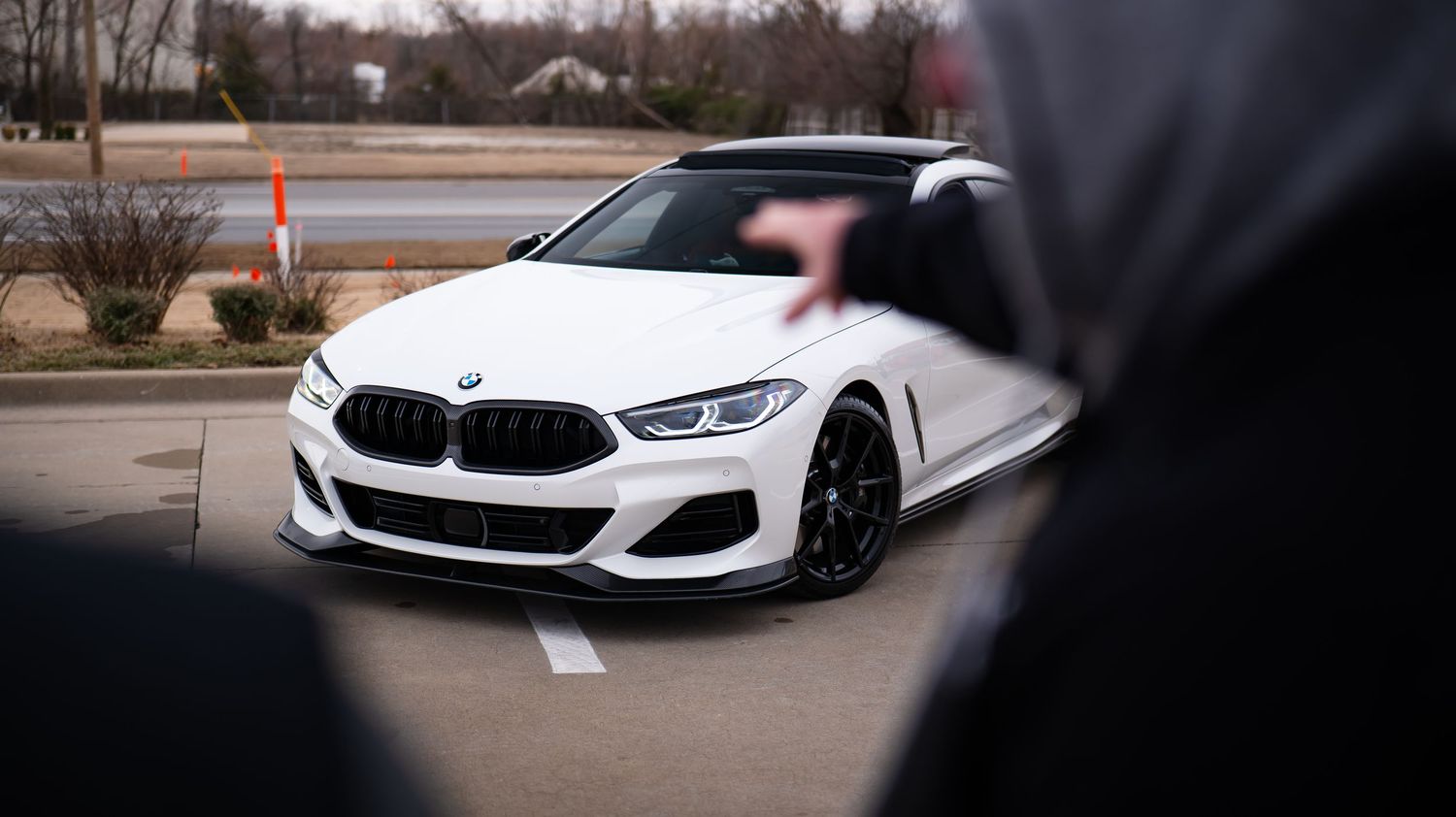 White BMW 8 Series sedan parked in a lot showcasing its sporty front design.