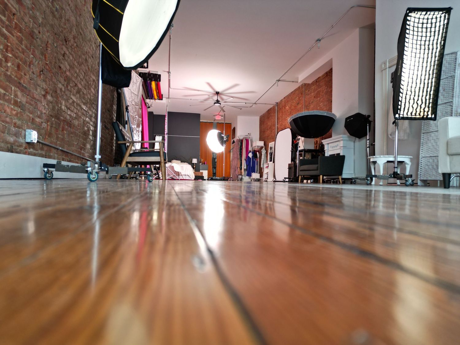 Professional photo studio space with polished hardwood floors and studio lighting equipment setup.