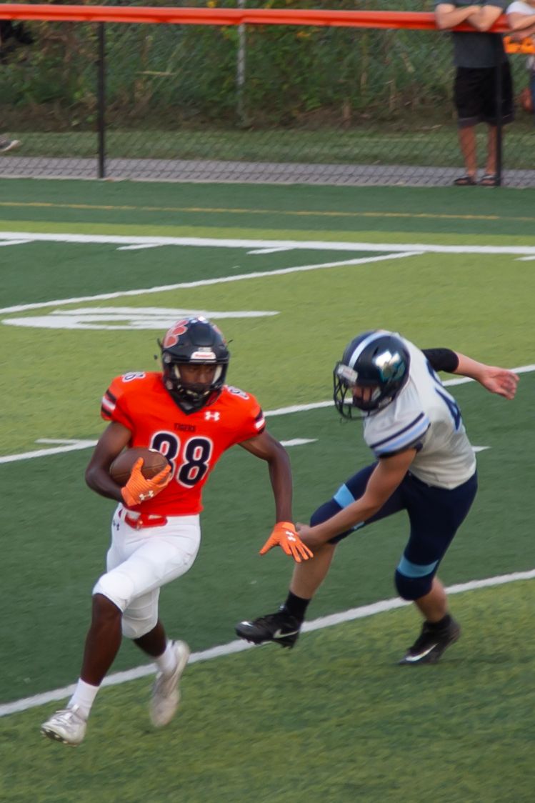 Football players demonstrating tackling techniques on practice field.