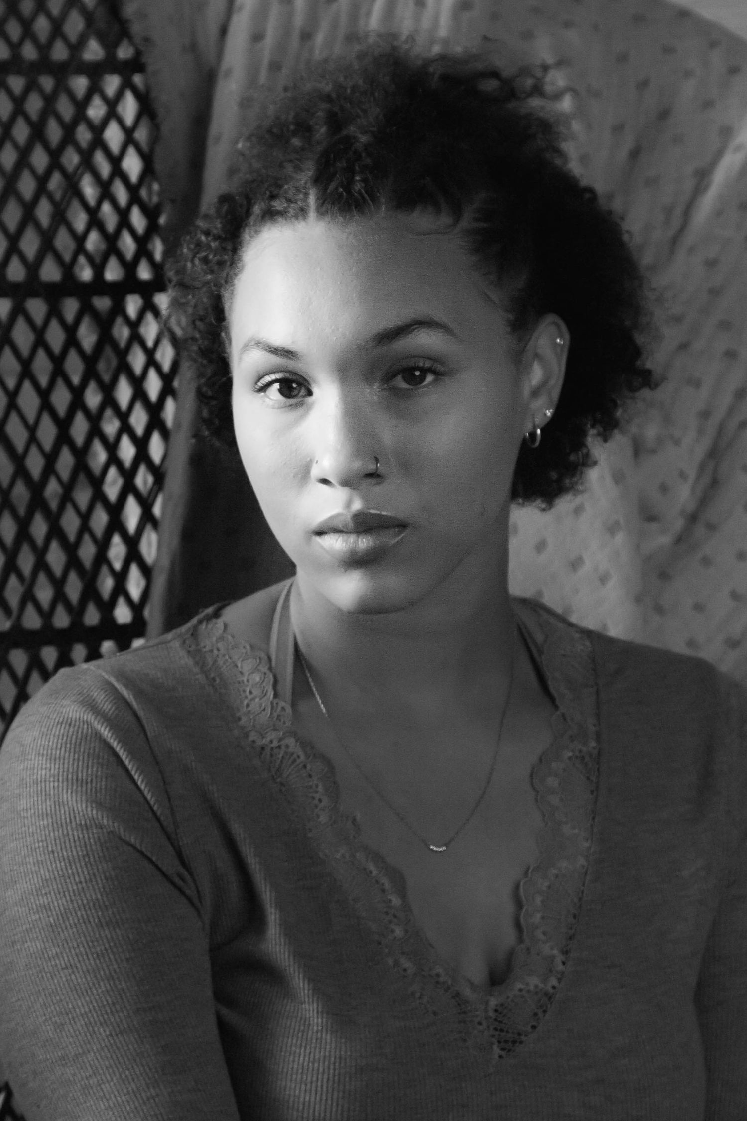 Black and white portrait series showing dramatic lighting and natural curls against textured background.