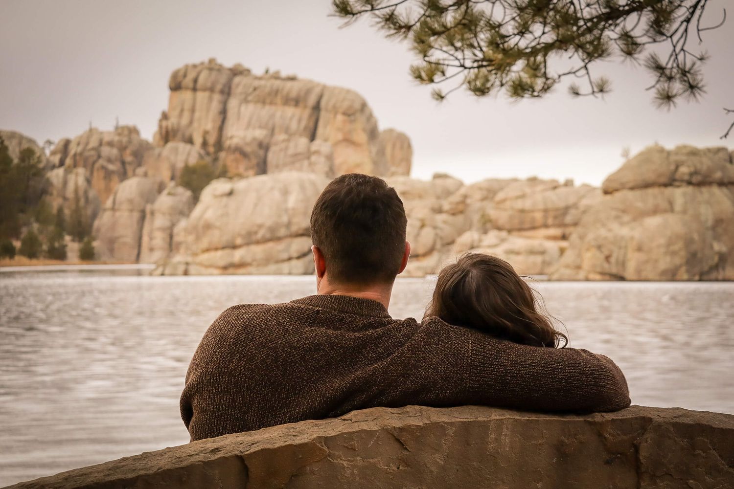 Engaged couple sitting on a bench.