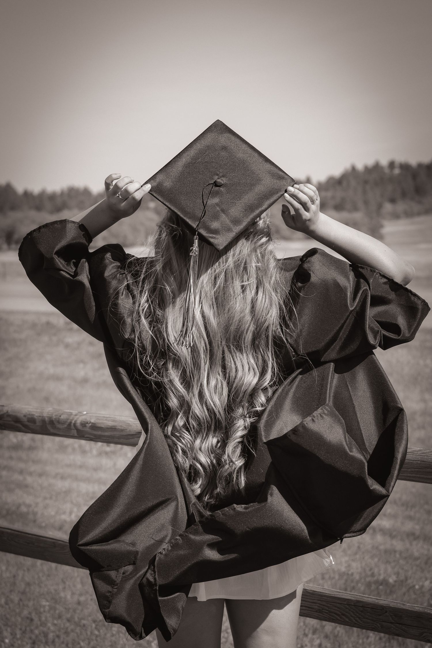 Senior photo of a girl in black and white with graduation cap, facing away from the camera.
