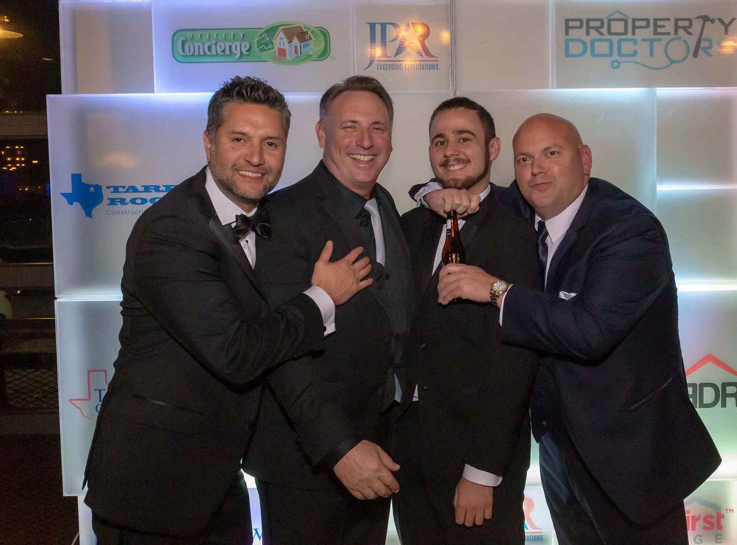 Business professionals pose together at a corporate event with branded backdrops.