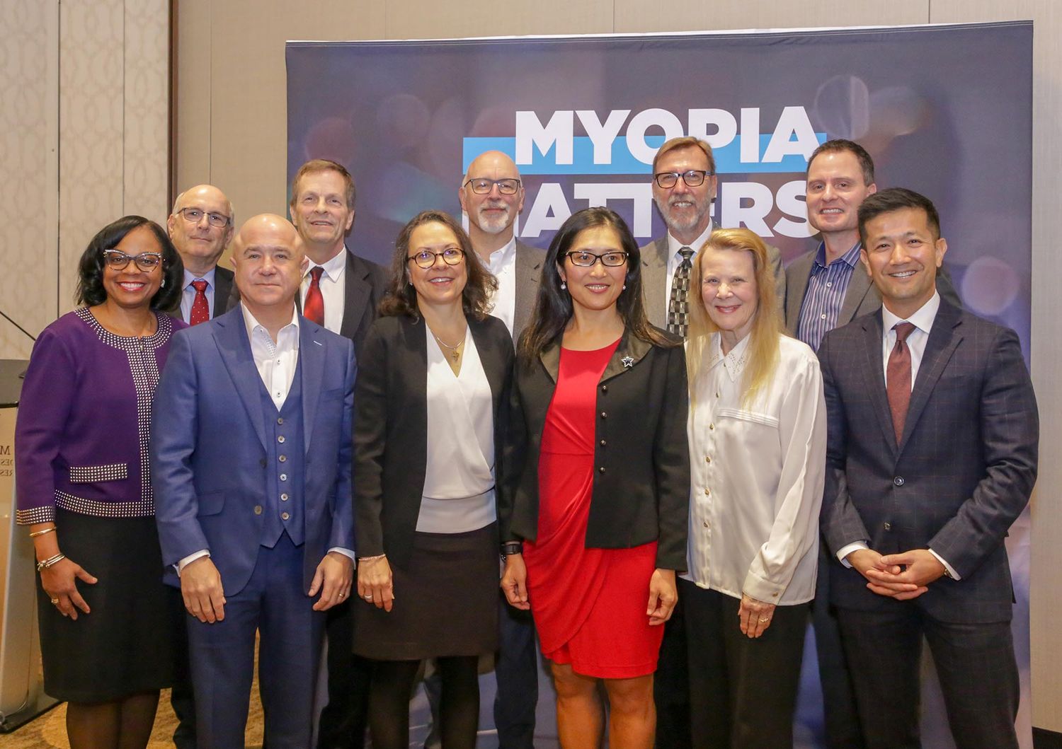 Group photo of business professionals standing together in front of a Myopia Matters banner.