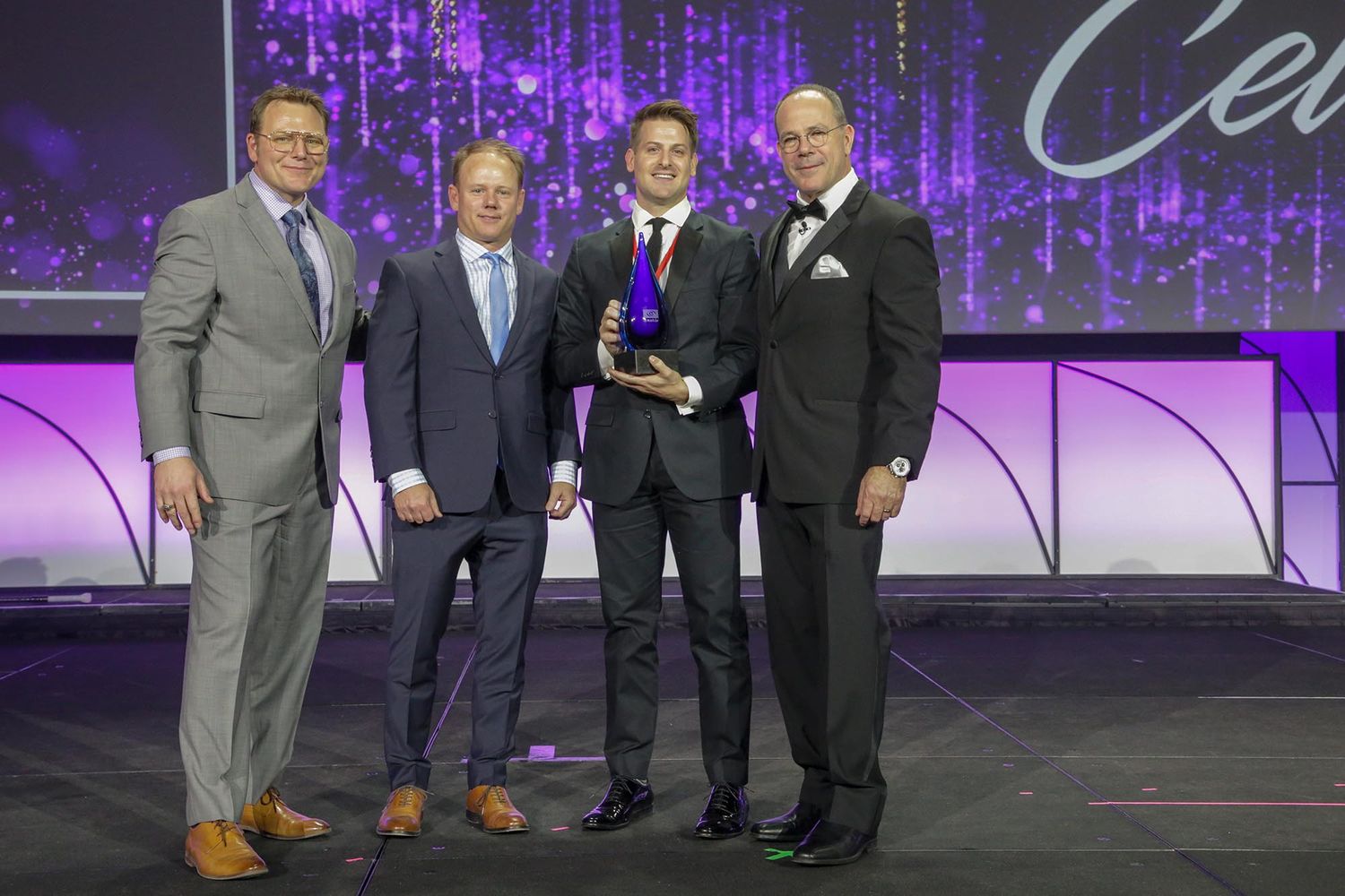 Award ceremony presentation on stage with elegant purple lighting and decor.