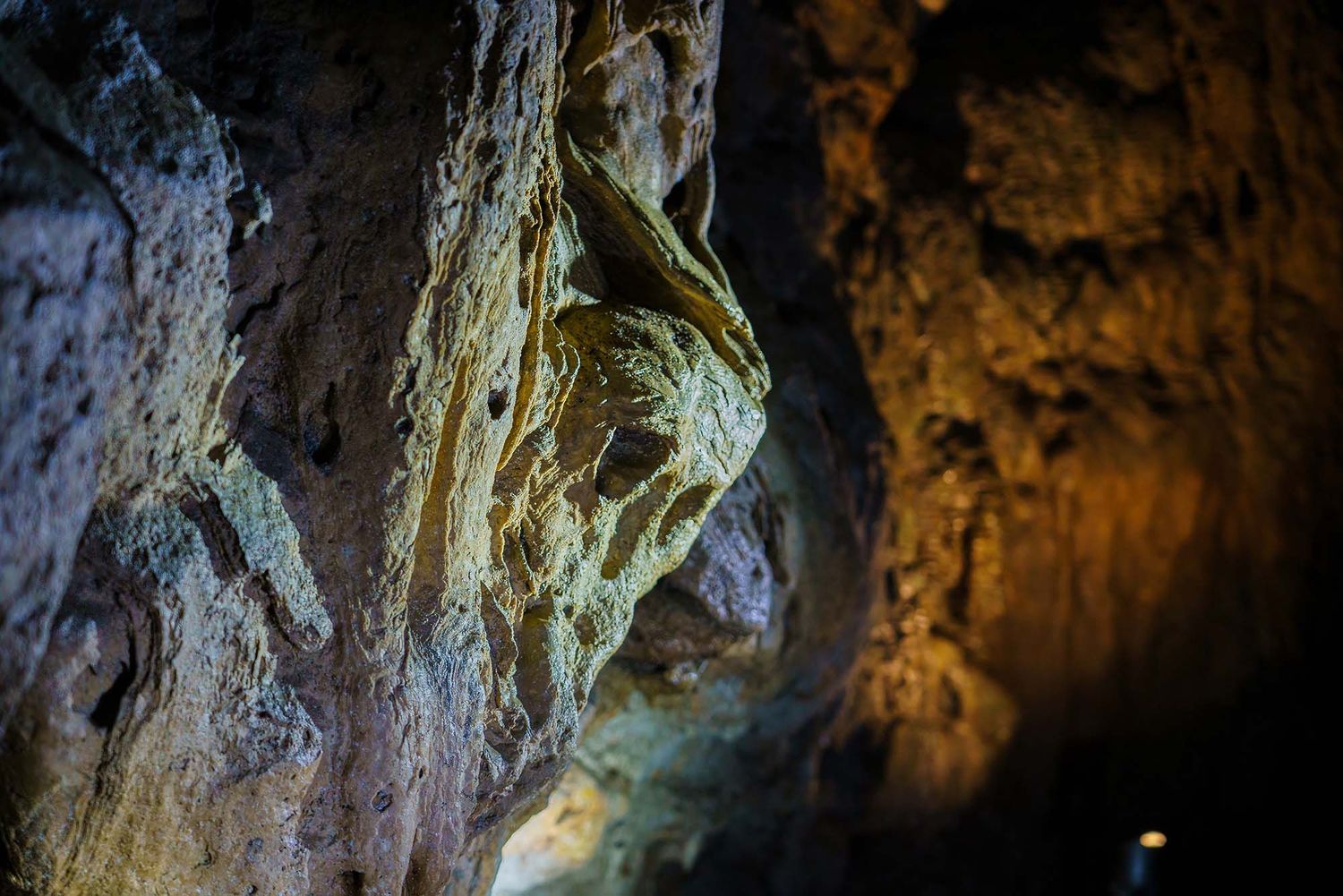 Natural limestone cave formations illuminated with dramatic lighting in an underground cavern.