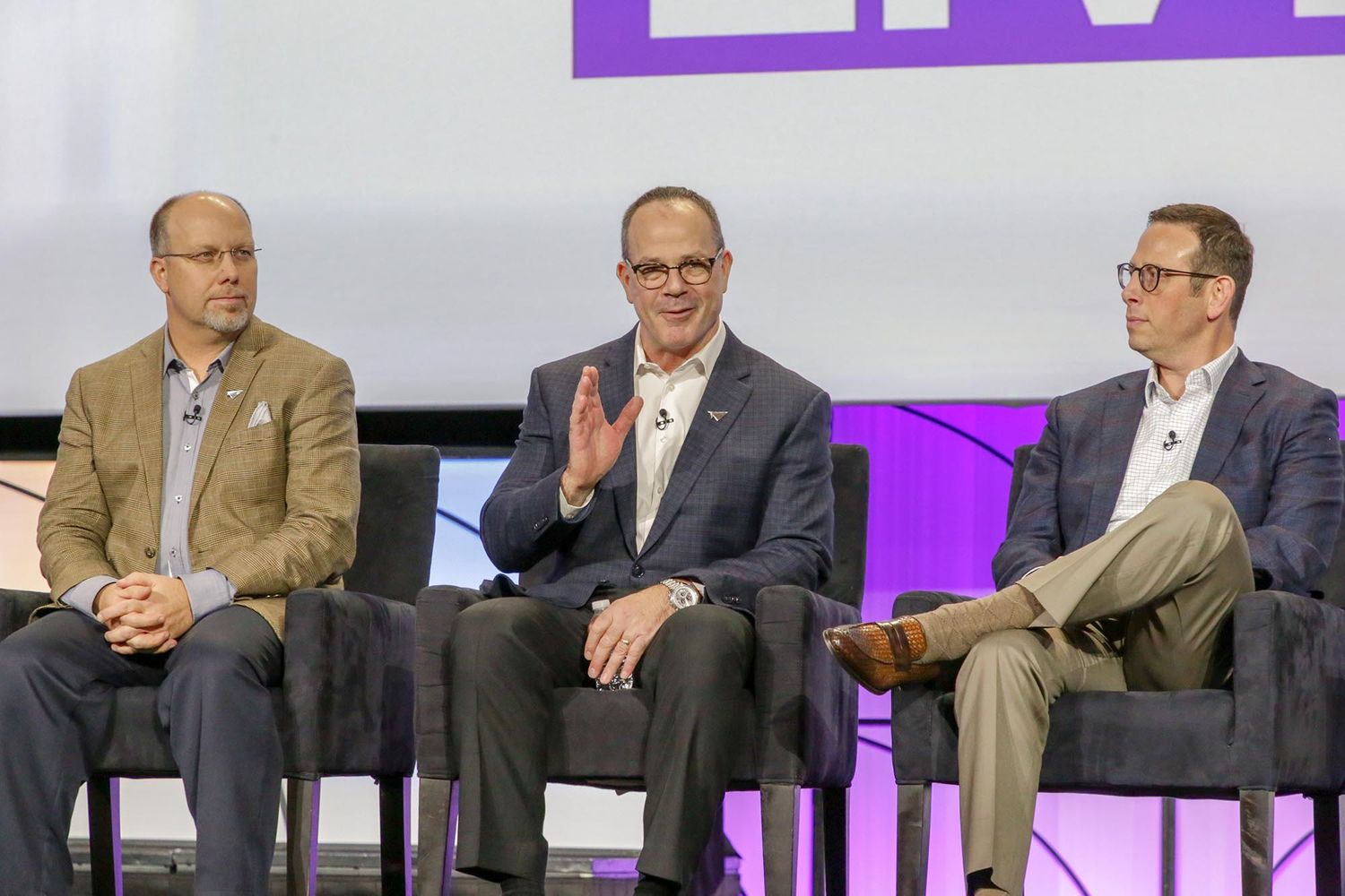 Three business professionals participating in a panel discussion on stage.