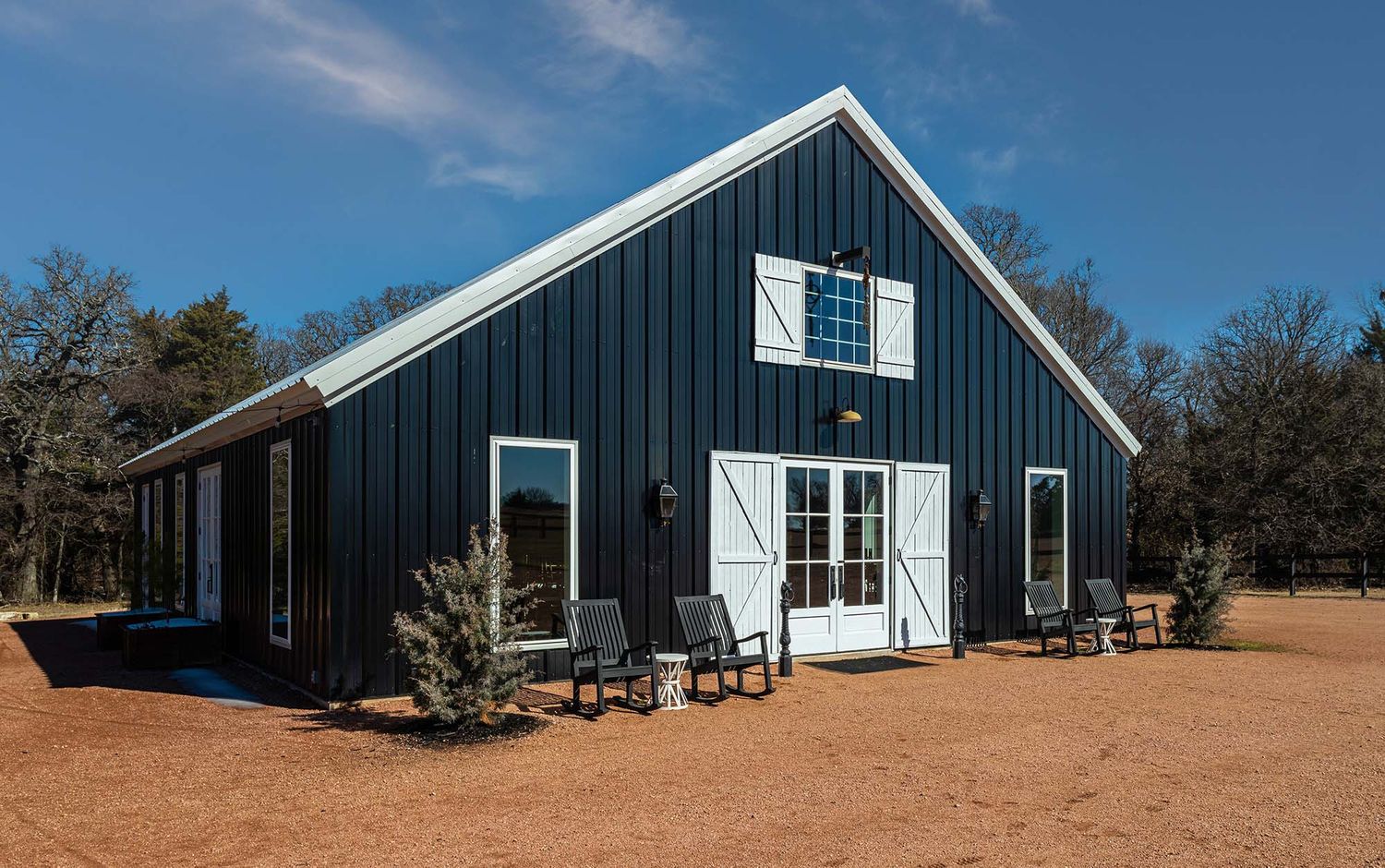 Modern navy blue barn-style buildings with white trim against a clear sky.