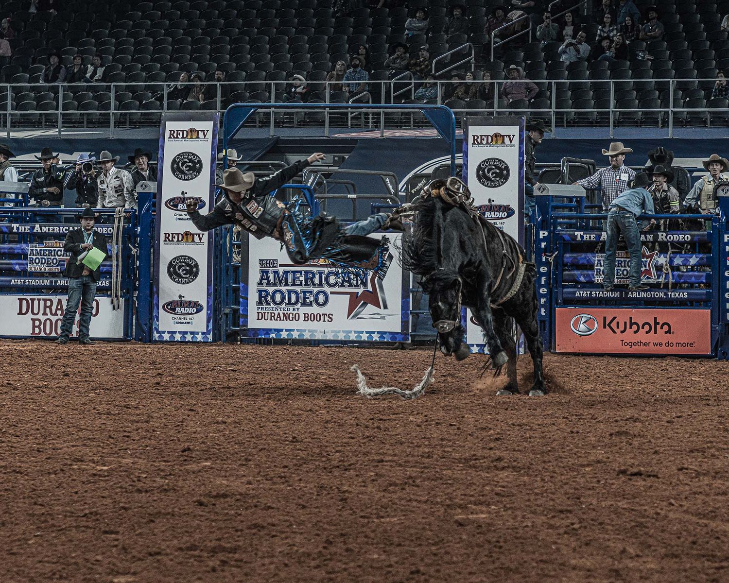 Empty rodeo arena with sponsor banners and stadium seating visible.