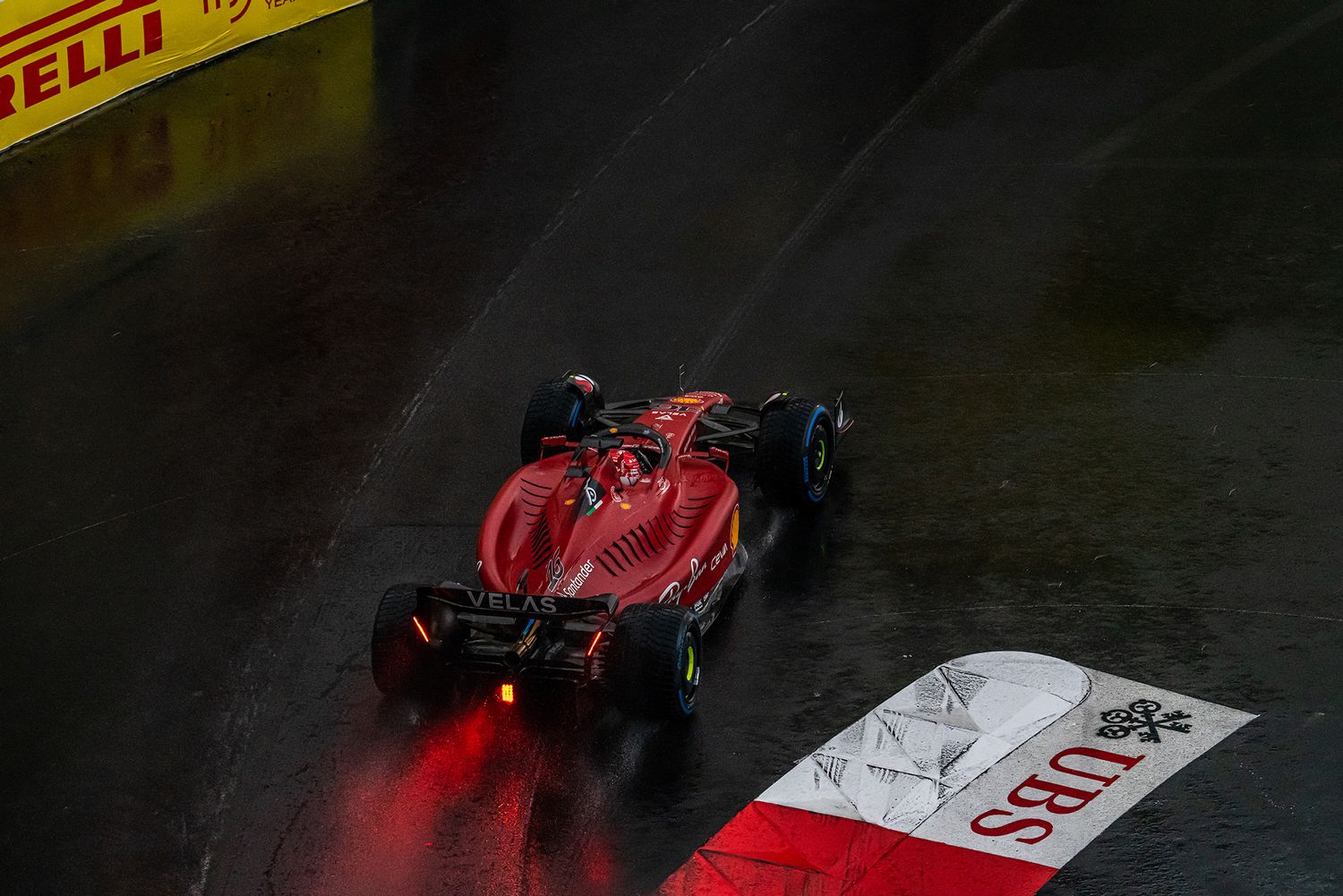Formula 1 racing cars with Pirelli branding captured in dramatic low-light conditions.