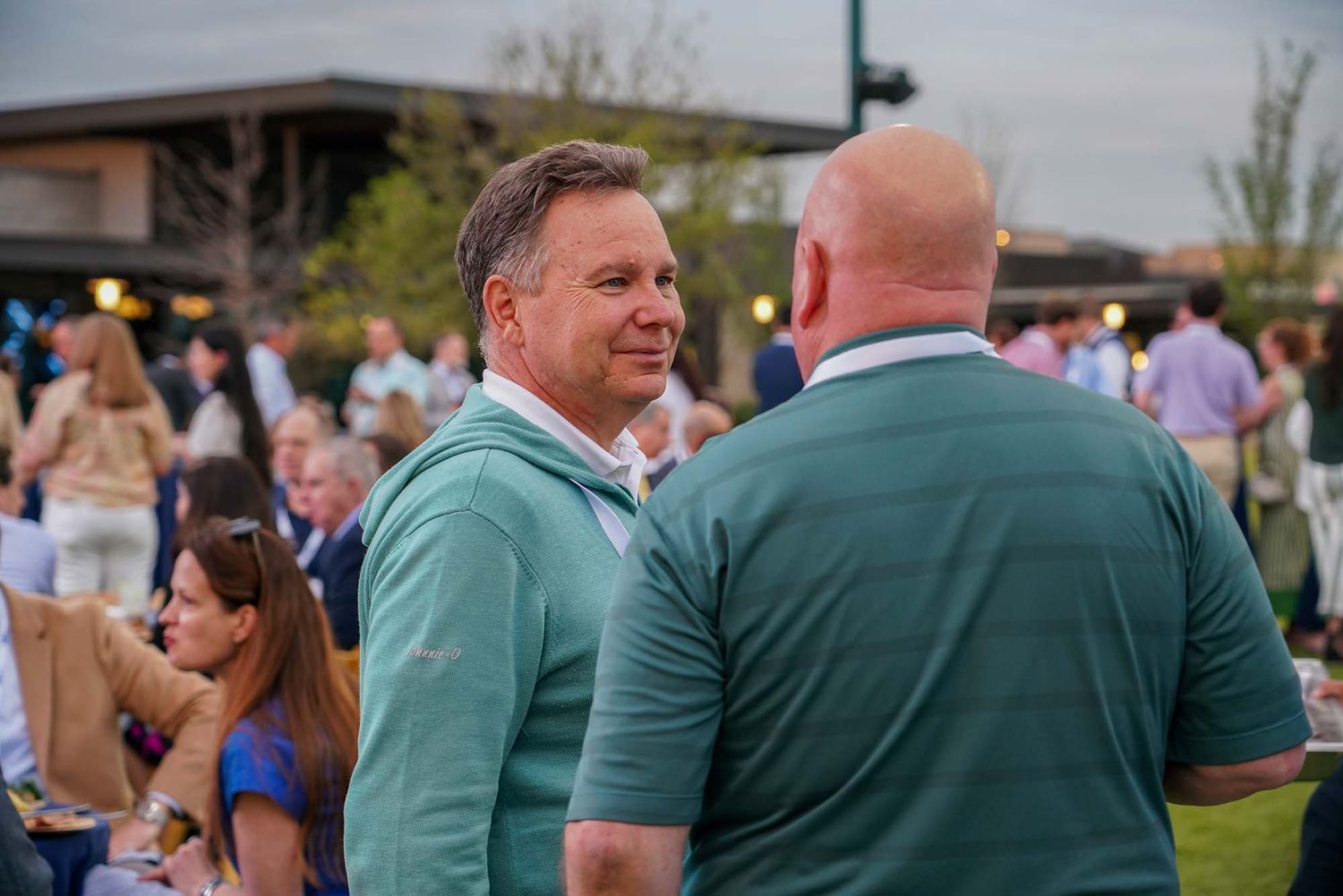 People mingling outdoors at a social event on a sunny day.