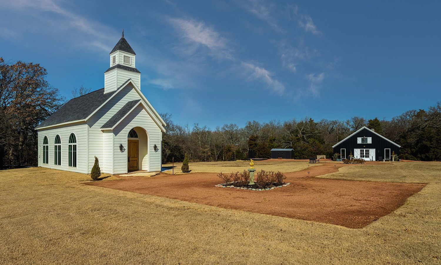 A panoramic view of rural churches and buildings scattered across rolling hills under a bright blue sky.