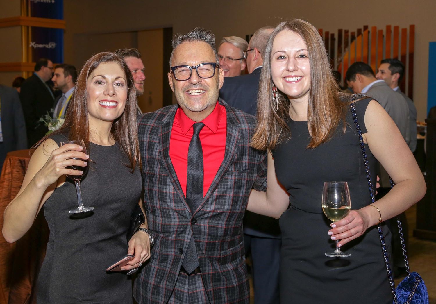 Three attendees enjoying drinks at an evening social gathering.