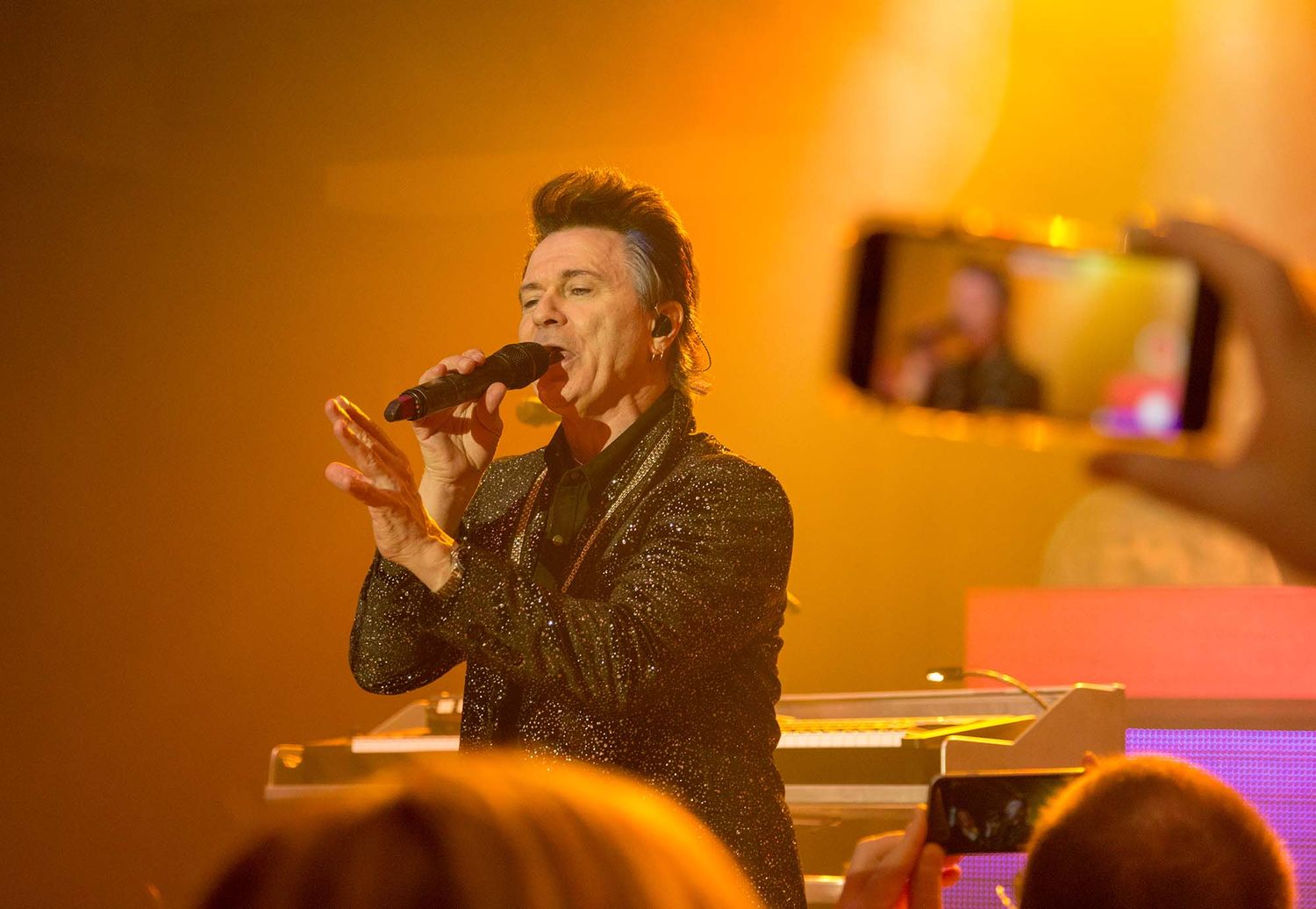 Concert performance with warm orange lighting and stage effects.