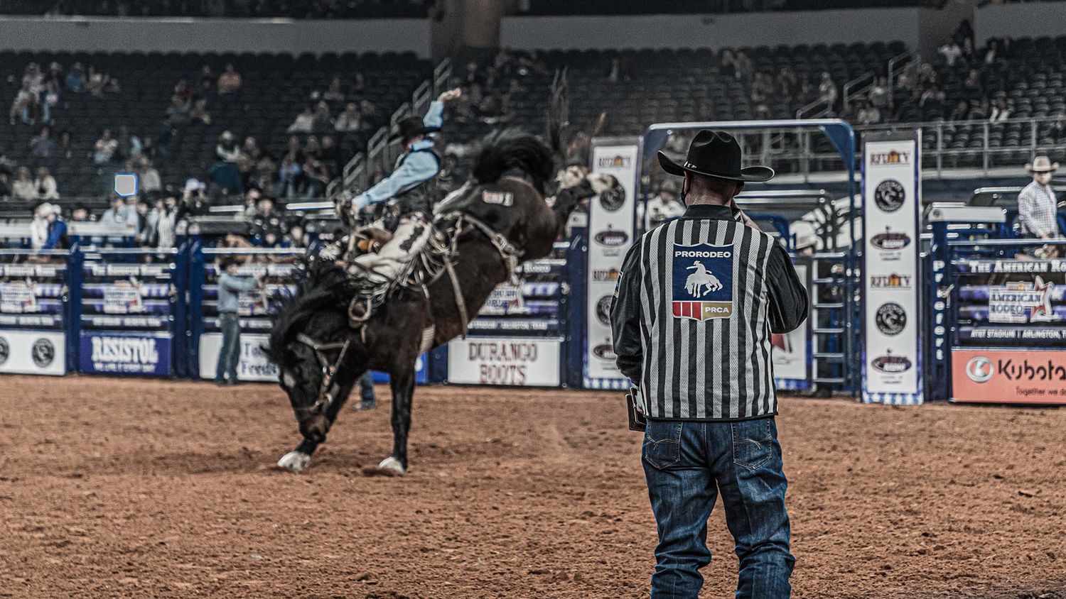 Rodeo action scene in arena with participant and officials visible.