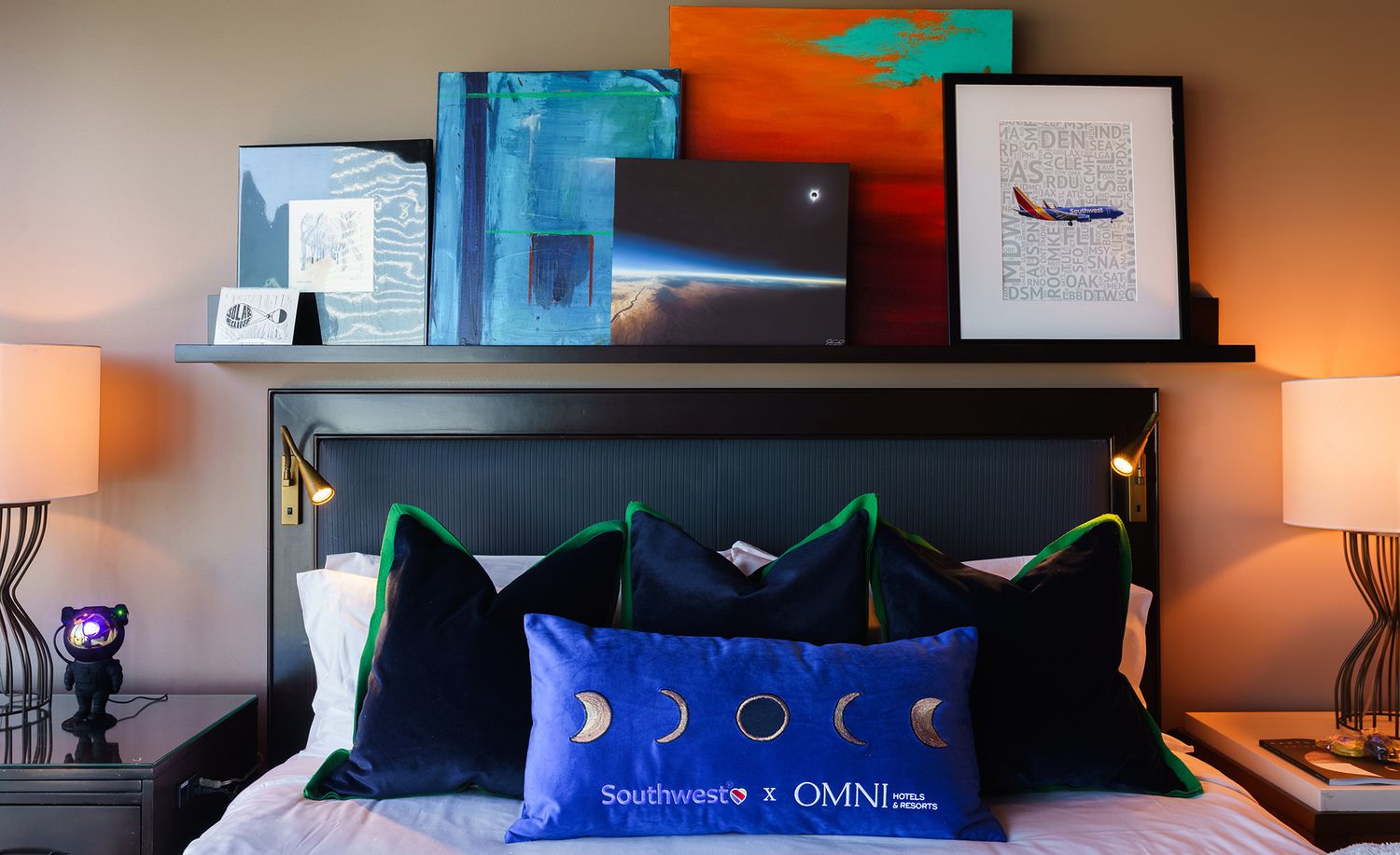 Contemporary hotel room with orange and blue color scheme featuring modern artwork and bedding.