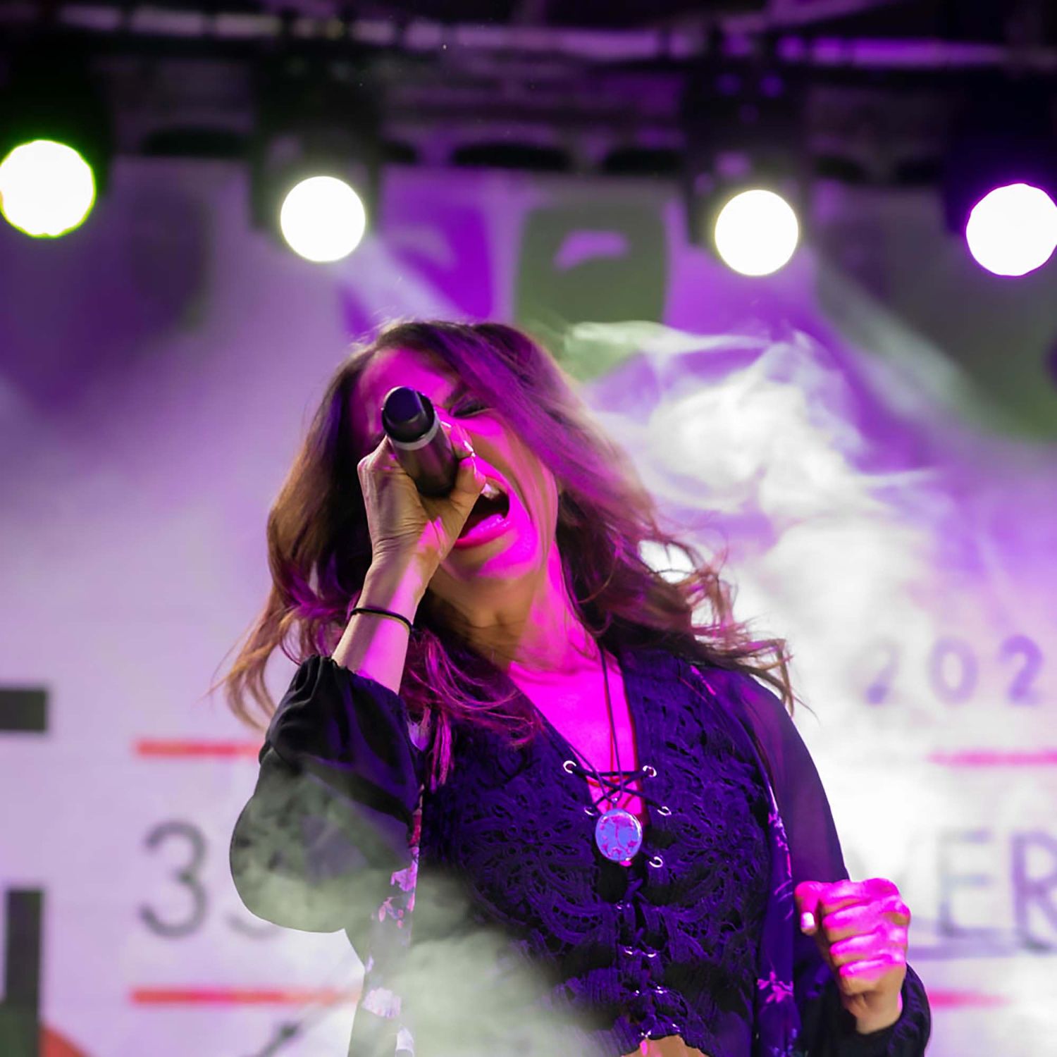 Concert performance with purple stage lighting and dramatic smoke effects.