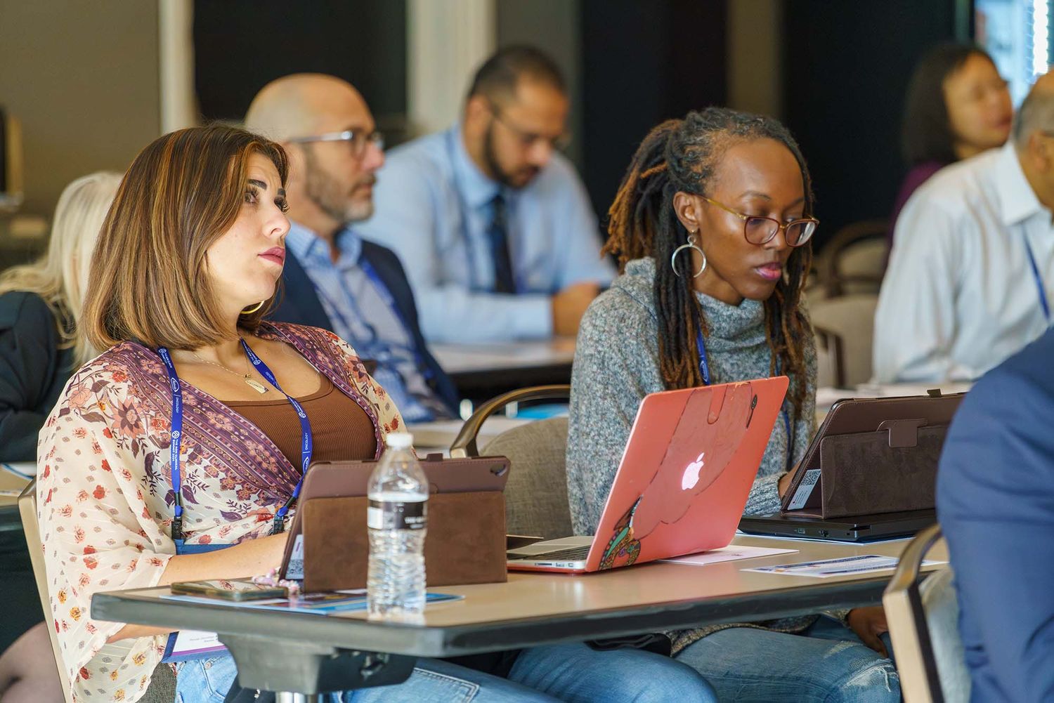 Diverse group of professionals participating in a business meeting or workshop around tables.