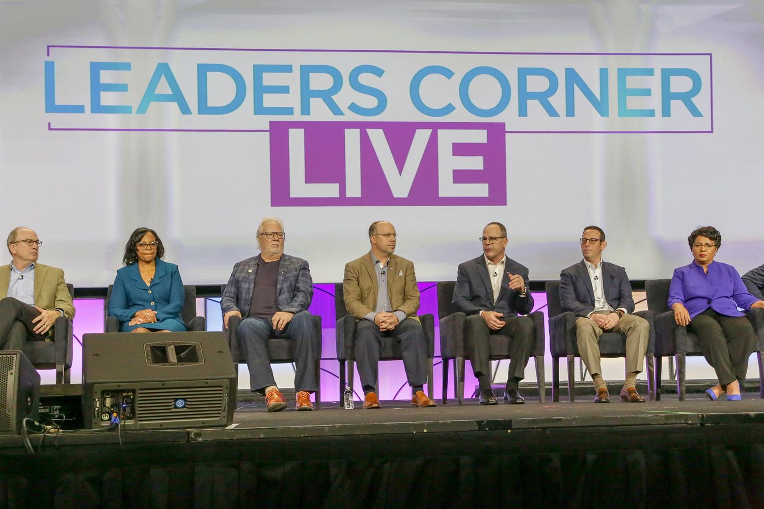 Panel discussion titled Leaders Corner Live with multiple speakers seated on stage.