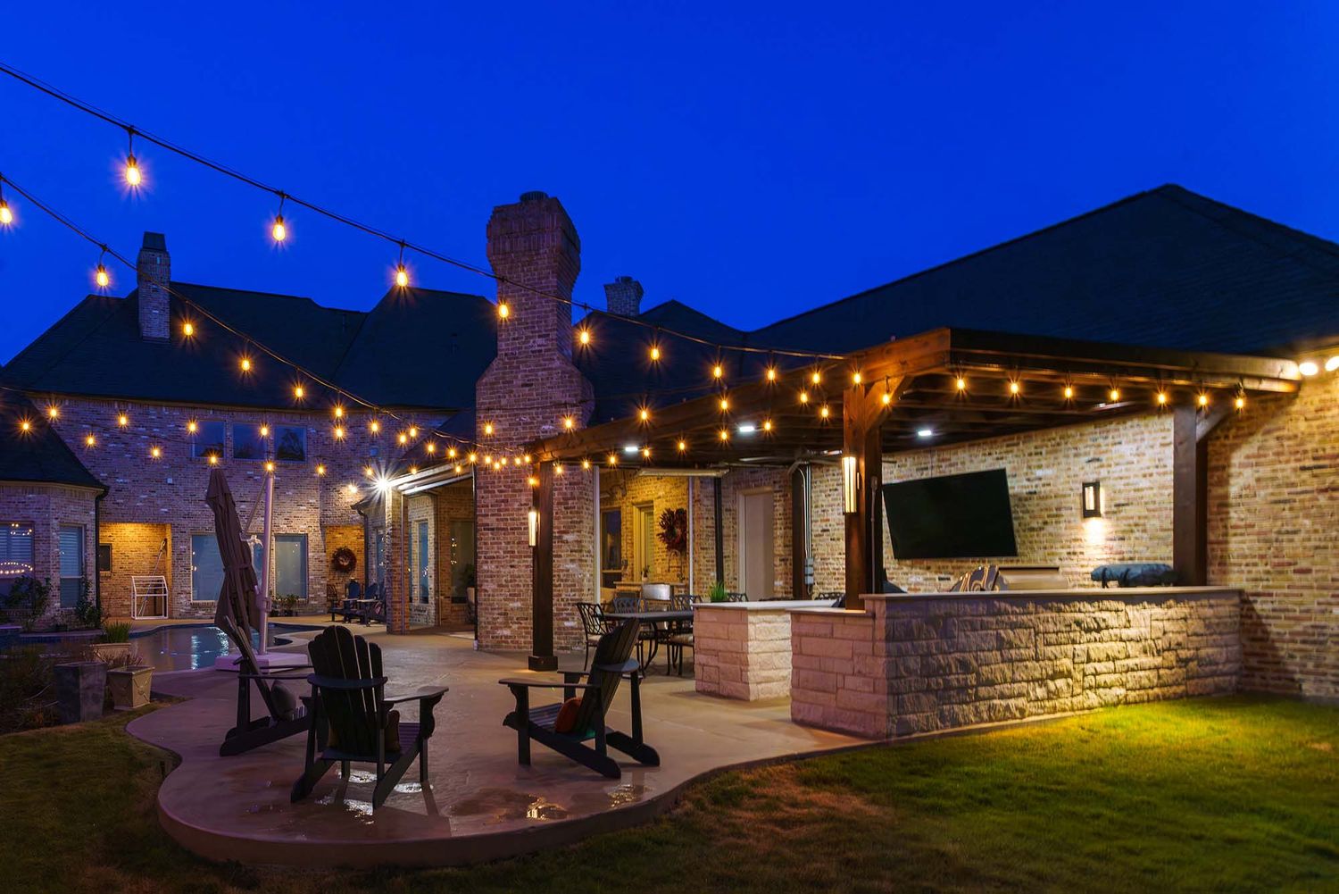 String lights illuminate an outdoor patio space at dusk creating a warm ambiance.