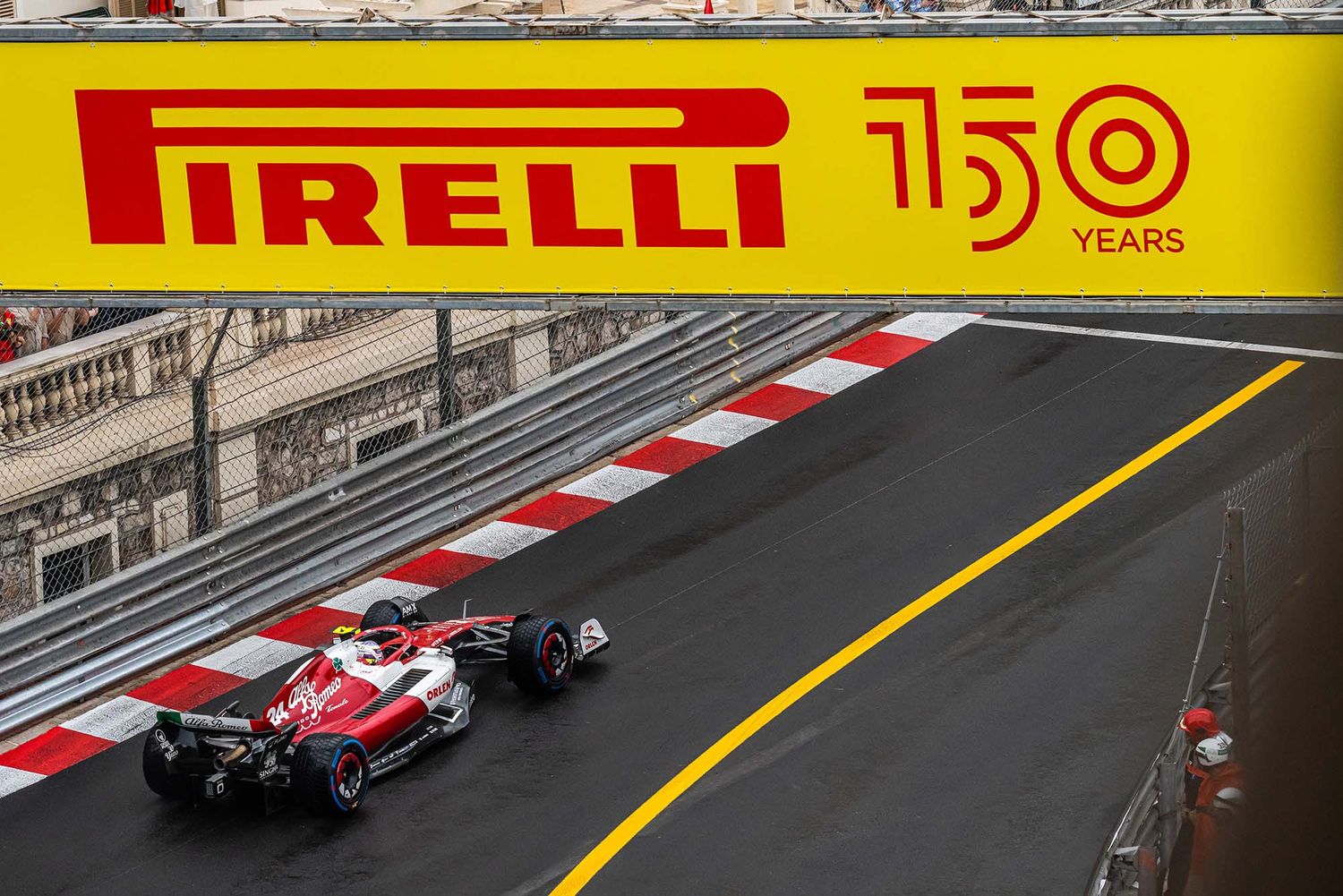 Formula 1 race cars competing on a street circuit with Pirelli advertising banners.